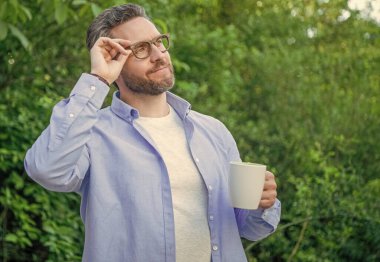 Açık havada kahve içen düşünceli bir adam. Kahveli bir adamın yaşam tarzı fotoğrafı. Kahveli bir erkeğin yaşam tarzı. Sabahları kahve içen bir adam..