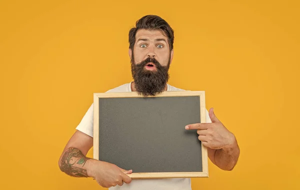 shocked man presenting sale in studio. photo of man presenting sale at blackboard. bearded man presenting sale isolated on yellow. man presenting sale on background with copy space.