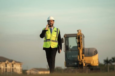 Mimar işgali adamı dışarıda telefonla konuşuyor. Mimar işgali mühendisi kask takıyor. Mimarlık mesleğinin fotoğrafı. Mimar işgali adamı..