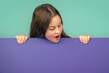 Reklam için fotokopi alanı olan boş mavi kağıdın arkasında büyülenmiş bir çocuk..