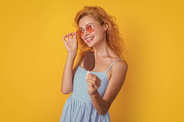 Stüdyoda dondurmalı pozitif kadın. Arkasında dondurma olan bir kadın. Yazın dondurmalı bir kadının fotoğrafı. Dondurmalı kadın sarıda izole edilmiş..