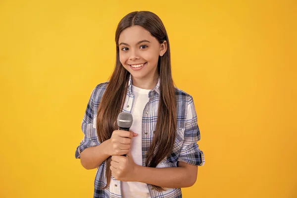 tween girl singer perform karaoke isolated on yellow background. With microphone in hand teenage girl singer. young karaoke singer girl hold microphone. teen girl singer hold mic in studio.
