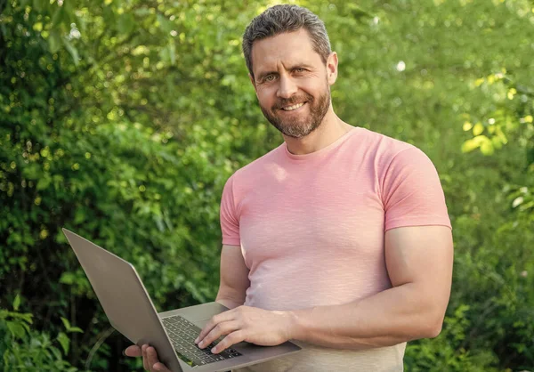 happy freelancer man with laptop. freelancer man outdoor. freelancer man work online. photo of freelancer man freelancing.
