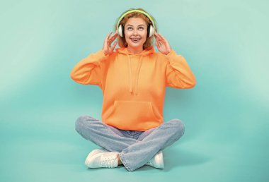 Olumlu bir kadının fotoğrafı müzik tarzı kulaklık takıyor. Kadının müzik yaşam tarzı mavi üzerine izole edilmiş. Kadının stüdyoda müzik tarzı var. Kadının arka planda müzik tarzı var..
