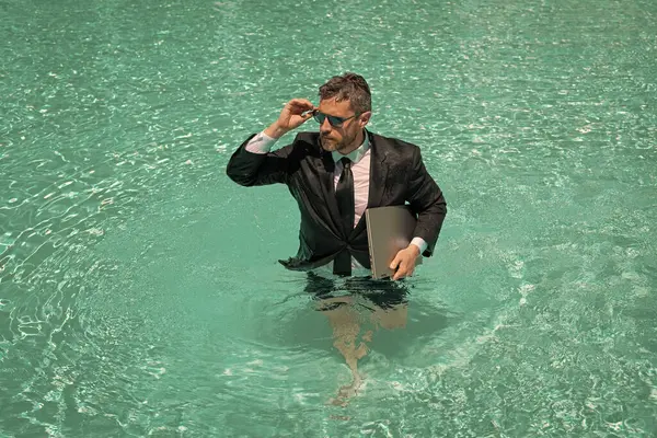 image of businessman has freelance business in pool. businessman has freelance business online. businessman has freelance business in swimming pool. businessman has freelance business with laptop.