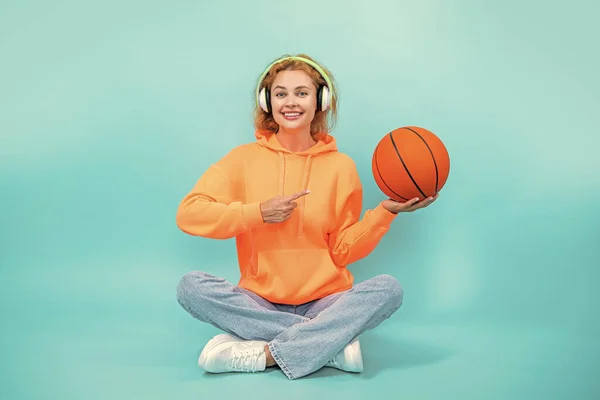 basketball woman loves music isolated on blue, point finger. basketball woman listen music in studio. basketball woman listening music on background. photo of basketball woman loves music.