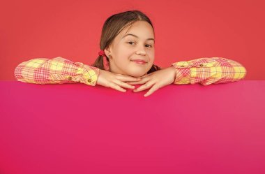 Reklam için fotokopi alanı olan boş pembe kağıdın arkasında gülümseyen çocuk..