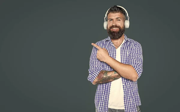 stock image positive bearded man listen to music pointing finger on headphones.