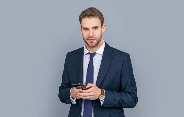 Casual business man chatting on phone isolated on grey. Businessman using phone. Man phone conversation in studio. Young business man with phone. Business communication. checking for messages.