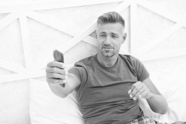 Yatak odasında telefonu olan bir adam var. Telefonlu tişörtlü video adam. Yatağında telefonla konuşan bir adam. Evde telefonlu bir video görüntüsü var..