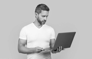 Sarı arka planda dizüstü bilgisayarı olan serbest çalışan bir adam. Adam dizüstü bilgisayarda çalışıyor. Serbest çalışan bir adam internette çalışıyor. Stüdyoda serbest çalışan bir adam..