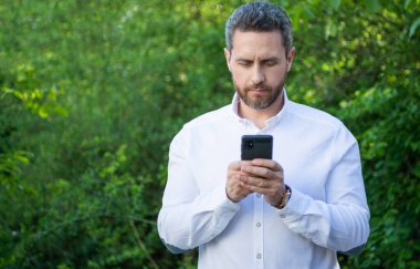 Telefonlu pazarlama işadamı, fotokopi alanı. Açık havada telefonu olan pazarlama işadamı. İnternette telefon işi yapan pazarlama işadamı. Telefonlu pazarlama işadamının fotoğrafı.