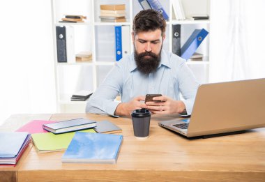 Ofis masasında oturan ciddi bir iş adamı cep telefonuna mesaj atıyor..