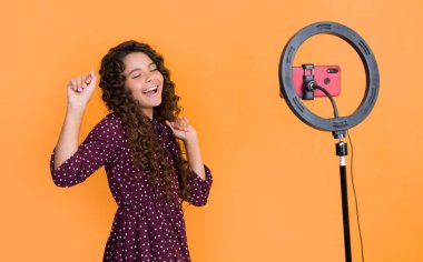 Mutlu çocuk uzun kıvırcık saçlarıyla blogda video çekerken iyi eğlenceler..