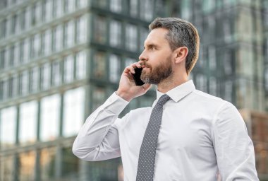 Patron akıllı telefon konuşması yapıyor. Patronun akıllı telefon konuşması. Akıllı telefonlu patron konuşuyor. Akıllı telefonlu patronun iş görüşmesi..