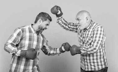 Kızgın iki nesil savaşıyor. Sarıda izole edilmiş. Stüdyoda kavga eden nesiller. Neslin erkekleri arka planda savaşıyor. Dövüş kuşağının fotoğrafı Boks eldiveni takıyor.