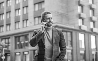 Gülümseyen iş adamı sokakta cep telefonuyla konuşuyor. İş adamı dışarıda cep telefonundan arıyor. İş adamının cep telefonuyla yaptığı telefon görüşmesinin fotoğrafı. İş adamının dışarıda cep telefonu görüşmesi var..