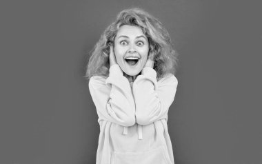 Renkli arka planda mutlu, kızıl saçlı, stil sahibi bir kadın. Kırmızı arka planda izole edilmiş şık bir kadın. Stüdyoda şık bir kadın. Kapüşonlu şık bir kadının fotoğrafı..