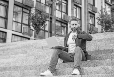 İnternette kulaklıkla internetten kontrol edilen adamın fotoğrafı. Man Webinar açık havada. Adam sokakta internetten internete düştü. Man webinar dışarıda..