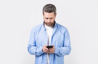 Olgun bir adam stüdyo arka planında izole bir şekilde telefonla mesaj yazar. Stüdyoda mesajı olan bir adam var. Erkek telefonundan mesaj var. Telefon mesajı gönderen adamın fotoğrafı.