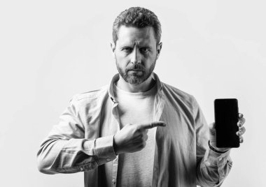 Adam telefon uygulamasını işaret ediyor. Telefon uygulaması gösteren adamın fotoğrafı. Stüdyonun arka planında izole edilmiş bir telefon uygulaması var. Stüdyoda telefon uygulaması gösteren adam.