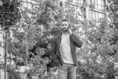 Adamın açık havada akıllı telefon görüşmesi var. Sokakta akıllı telefon görüşmesi yapan bir adam. Adam dışarıdaki akıllı telefondan arıyor. Adamın fotoğrafı. Akıllı telefondan ara ve konuş..