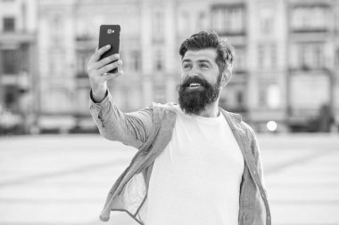 Gezici internet üzerinden video görüşmesi yapan mutlu bir adam. Sakallı adam akıllı telefona gülümsüyor. Mobil internet kullanıcısı. Cep telefonu uygulaması kullanılarak çevrimiçi arama. Mobil iletişim.