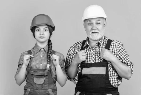 stock image teen girl and granddad builder in helmet on yellow background.