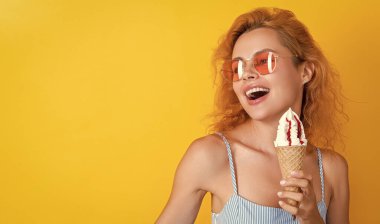 Yazın dondurma yiyen kadın, fotokopi uzayı. Külahta dondurması olan kadın sarıda izole edilmiş. Stüdyoda dondurmalı bir kadın var. Arka planda dondurma külahlı kadın.