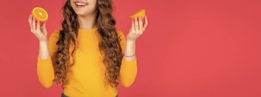 Mutlu genç kız pembe arka planda portakal meyvesi tutuyor..