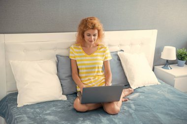 Gülümseyen kadın blogcu evde dizüstü bilgisayarla çalışıyor. Blogcu kadın evde çalışıyor. Blog yazarı için ev işi. Yatakta dizüstü bilgisayarlı bir kadın.