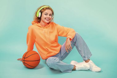 Pozitif sporcu kadın müziği sever. Sportif kadın mavi üzerine izole edilmiş müziği sever. Sportif kadın stüdyoda müzik dinliyor. Arka planda müzik dinleyen spor kadını.