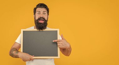 Sakallı adam sarı pankartta izole edilmiş bir ilan veriyor. Adam arka planda fotokopi alanı olan bir reklam sunuyor. Adam stüdyoda reklam veriyor. Bir adamın fotoğrafı tahtaya reklam veriyor.