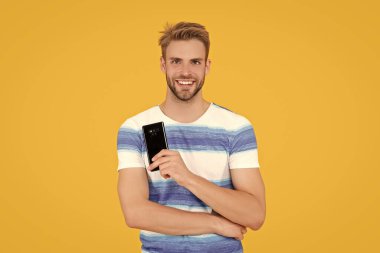 Stüdyoda telefon tutan gülümseyen bin yıllık adam sarı arka planda izole edilmiş..