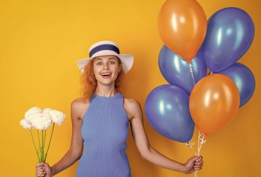 Kadınlar gününde balonlu ve çiçekli retro kız sarıda izole edilmiş. Stüdyoda elinde balonla dolaşan bir kız. Arka planda balonlu bir kız vardı. Balonlu kızın fotoğrafı.