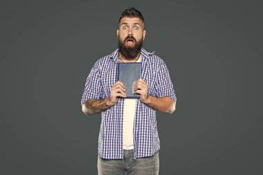 Açgözlü sakallı adam gri arka plan üzerine kitap tutuyor..