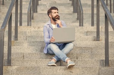 Düşünen adamın dışarıda online video iletişimi var. Adamın dışarıda çevrimiçi video bağlantısı var. Adamın merdivenlerde online video bağlantısı var. Adamın dizüstü bilgisayarında video bağlantısı var..