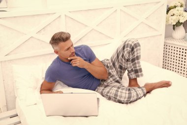 Düşünen adam evde yatakta serbest çalışıyor. Adam evde, yatak odasında serbest çalışıyor. Evde dizüstü bilgisayarlı serbest çalışan bir adamın fotoğrafı. Adam evde serbest çalışıyor..