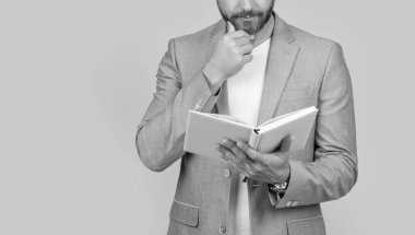 İnsan okuyucunun kitap okurken çekilmiş bir fotoğrafı. Adam okuyucu kitabı sarı arka planda izole edilmiş. Adam okuyucu ceketinde kitap okuyor. İnsan okuyucunun kitap okurken çekilen bir fotoğrafı..
