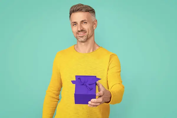happy man shopper with present isolated on blue. man shopper with present in studio. man shopper with present on background. photo of man shopper with present.
