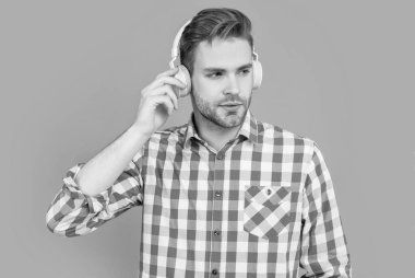 Üniversite öğrencisi öğrenim için kulaklık takıyor. Kulaklıkla ses kurslarını dinleyen ciddi bir adam. Mesafe öğrenme. Okul eğitimi. Uzak öğrenme.