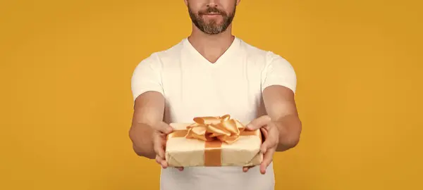 cropped view of man with gift box for holiday. photo of man holding occasion gift box. man hold gift box isolated on yellow background. man hold gift box in studio.