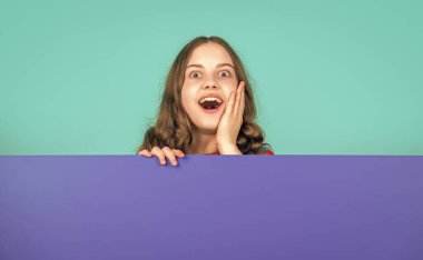 Reklam için kopya alanı olan boş mavi kağıtlı hayret bir çocuk..