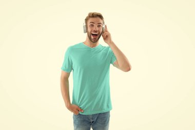 Müzik kulaklığı takmış şaşırmış bir adamın görüntüsü. Müzik kulaklıklı adam beyazda izole edilmiş. Arka planda müzik kulaklıklı adam var. Stüdyodaki müzik kulaklıklı adam..