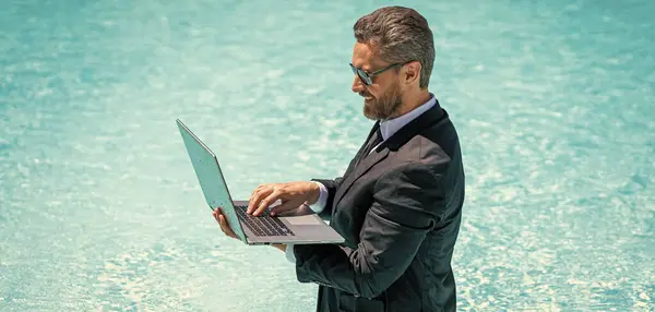 man trader work and relax with laptop. image of man trader work and relax in pool. man trader work and relax. man trader work and relax in swimming pool.