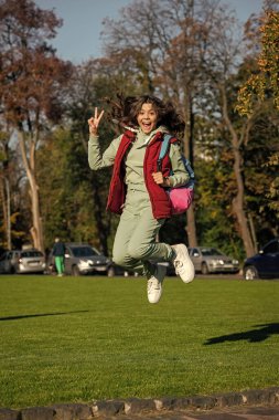 liseli kız dışarıda zıplıyor. Sırt çantalı liseli kız. Parktaki genç kızın fotoğrafı. Okullu genç kız..