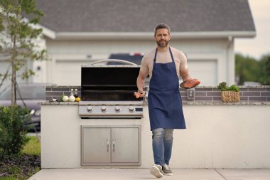 Neşeli adam açık havada deniz ürünleri barbeküsü pişiriyor. Adam somonlu deniz ürünleri barbeküsü pişiriyor. Adam balıkla mangal yapıyor. Adam deniz ürünleri barbeküsü pişiriyor..