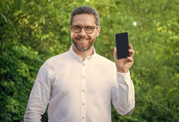 photo of cheerful businessman showing app with copy space. businessman showing app. businessman showing app outdoor. businessman showing app on phone.