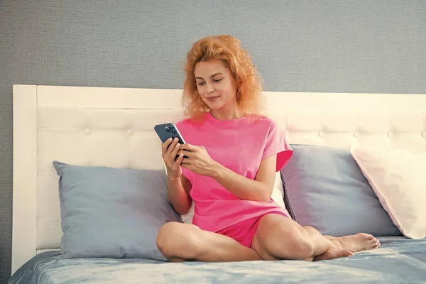 smiling girl relax at home and texting on phone. girl texting on phone on the bed. phone texting of girl.