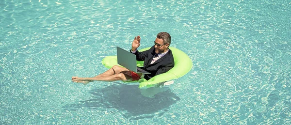 man has business video conference refreshing at pool. man has business video conference with laptop. photo of man has business video conference. man has business video conference.